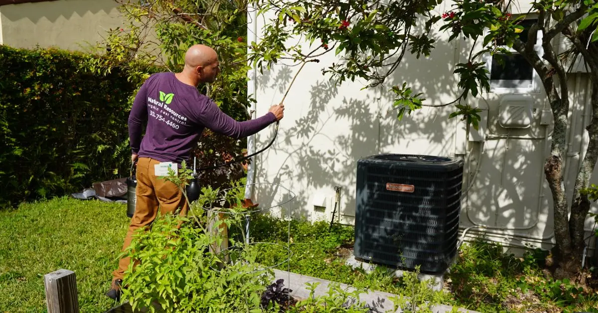 Pest control technician treating the exterior of a home